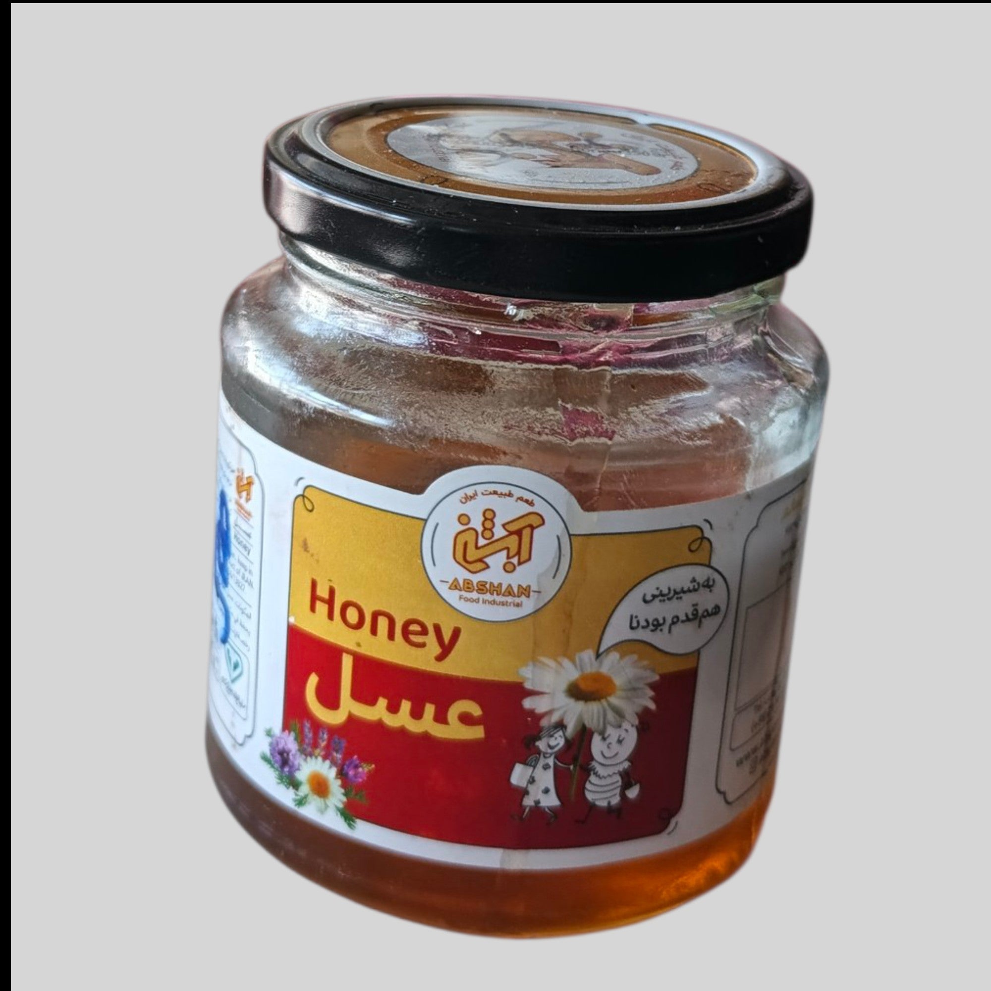 Jar of honey with a label on a light gray background